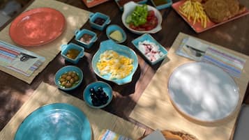 Una mesa al aire libre con varios platos, incluyendo platos hondos, tazones y cubiertos.
