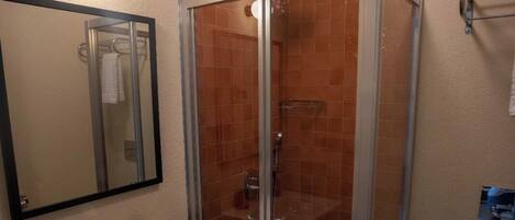 A bathroom with a glass shower enclosure, a white sink with a mirror, and a toilet.