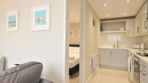 Eine moderne Wohnung mit Wohnbereich, einem Bett, einer Küchenzeile und zwei gerahmten Bildern an der Wand.