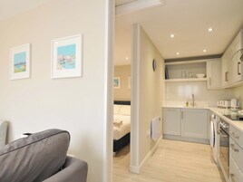 Un apartamento moderno con sala de estar, una cama, kitchenette y dos cuadros en la pared.