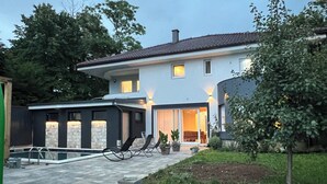 Een modern huis met twee verdiepingen, een zwembad, terras en een verzorgde tuin.