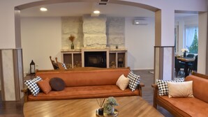 Een woonkamer met een houten salontafel, een oranje bank en een stenen openhaard.