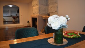 Een eetgedeelte met een houten tafel, een vaas witte bloemen en een bord met watermeloen.