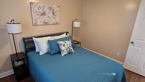 Un dormitorio con cama, ventilador de techo, lámpara de pared y una puerta.