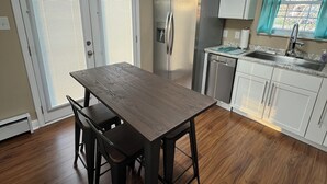 Una cocina con una mesa de madera, armarios blancos y un horno empotrado.