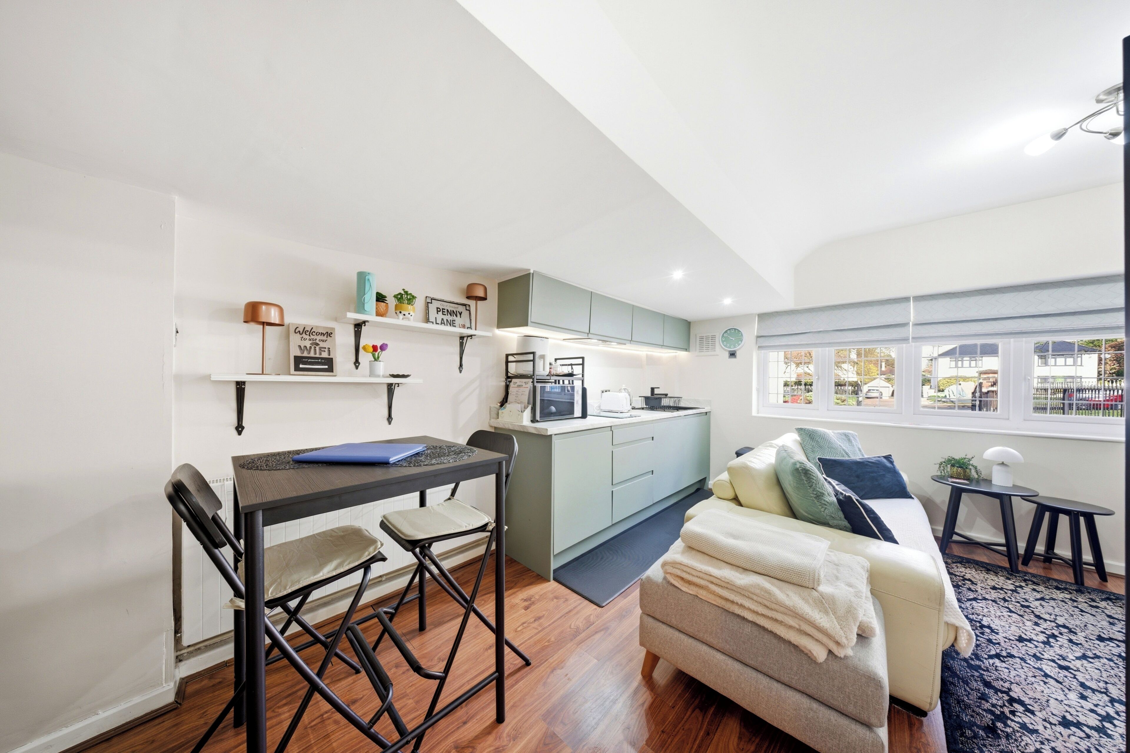 A compact living space with a kitchenette, a dining area, a sofa, and a view through large windows.