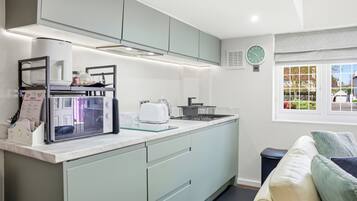 A compact kitchen with a built-in microwave, toaster, and sink. There is a window with a view of the outside.
