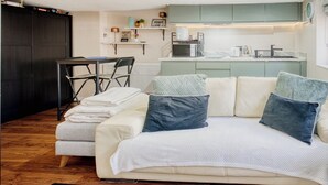 Un espacio habitable compacto con kitchenette, comedor y sofá con cojines.