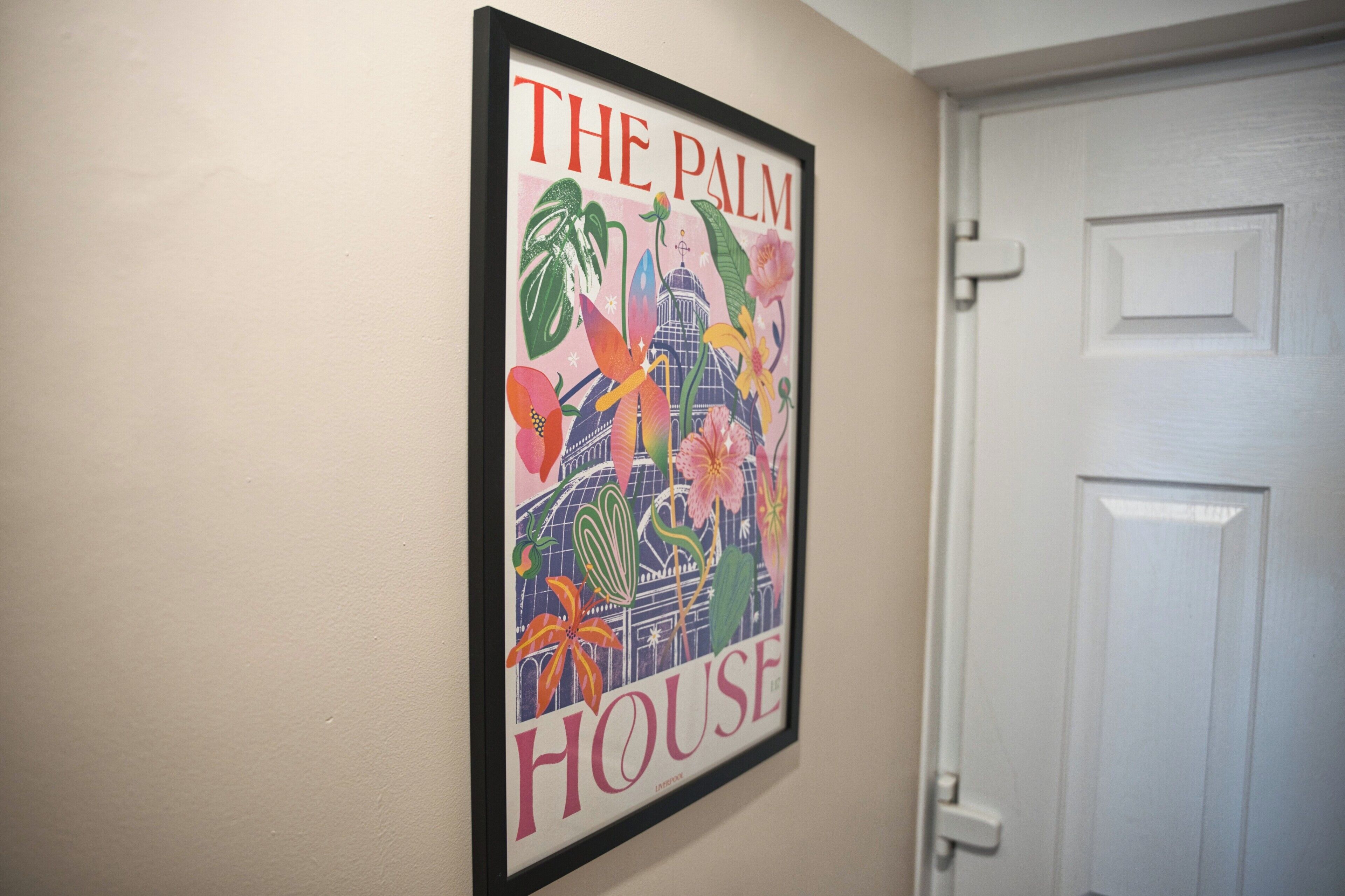 Une affiche encadrée avec le texte « THE PALM HOUSE » et des illustrations florales.