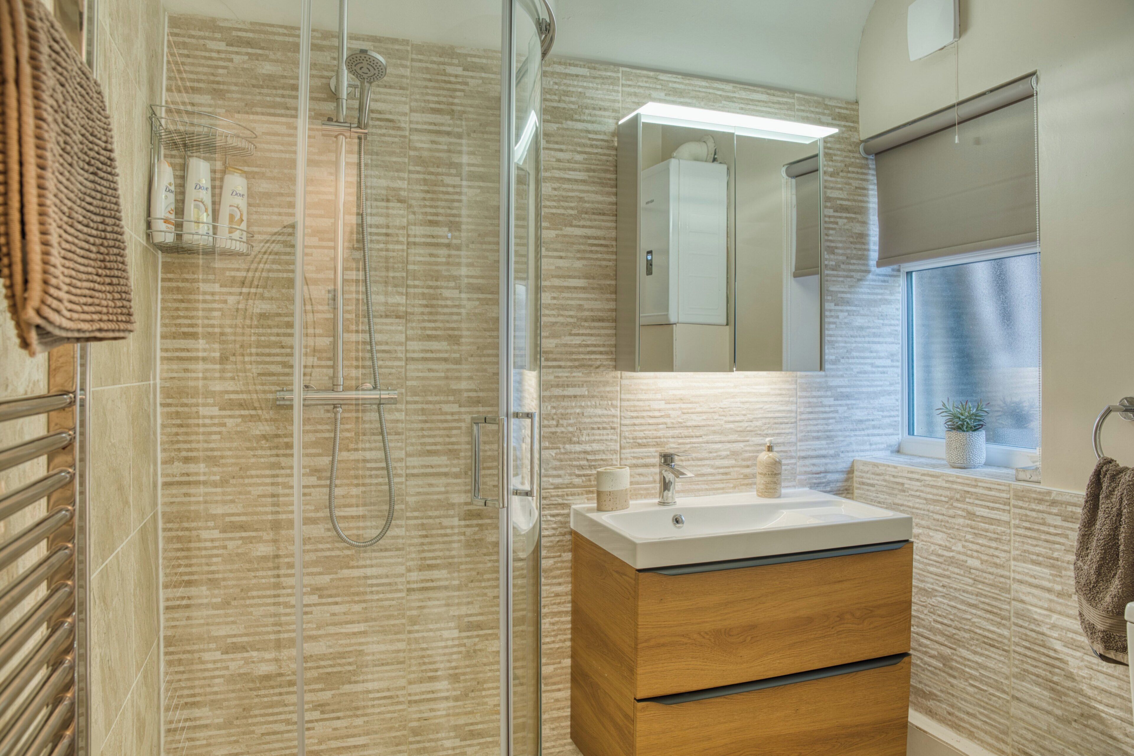 A modern bathroom with a glass-enclosed shower, a wooden vanity, and a large mirror.