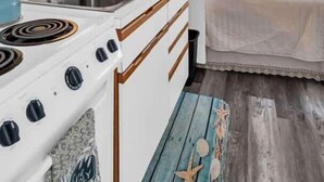 A compact kitchen with white cabinets, a microwave, a stove, and a sink.