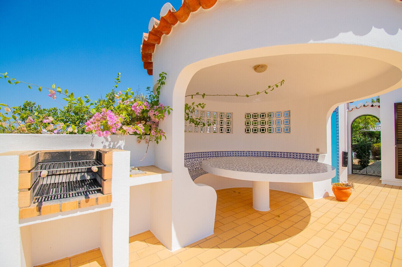 A patio area with a grill, seating, and decorative tiles.
