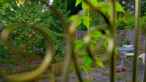A garden with a wooden fence, a stone pathway, and a small table and chair set. - 2BR Near Crouch Hill, Camden & Emirates Stadium (London)