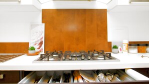 A modern kitchen with a white countertop, a gas stove, and wooden panel backsplash. - 2BR Near Crouch Hill, Camden & Emirates Stadium (London)