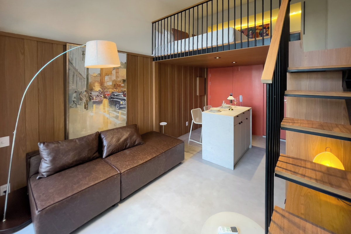 A modern interior with a brown leather sofa, a small island table, a staircase, and a cityscape mural.