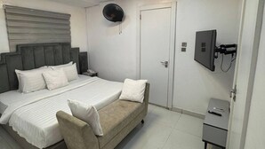 A modern bedroom with a bed, bedside table, and a TV mounted on the wall.