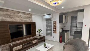 A modern living room with a flat-screen TV, a coffee table, and two sofas.