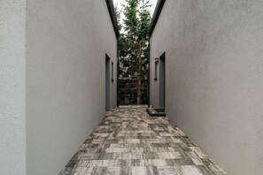 A corridor with a patterned floor leading to a door, flanked by plain walls and a tree in the background. - Holiday home near the sea, air conditioning (Sianozety)