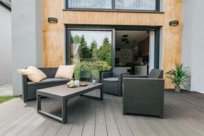 Un área de estar al aire libre con muebles de mimbre y una terraza de madera.