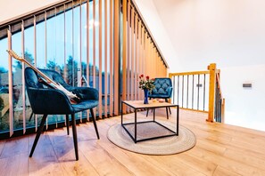 A modern living room with a large window, a wooden staircase, and a round coffee table. - Holiday home near the sea, air conditioning (Sianozety)