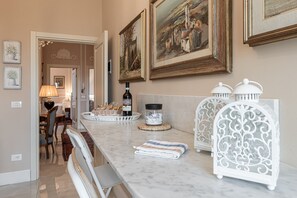 Una cucina con piani di lavoro in marmo, un'area pranzo con sedie e quadri appesi al muro.