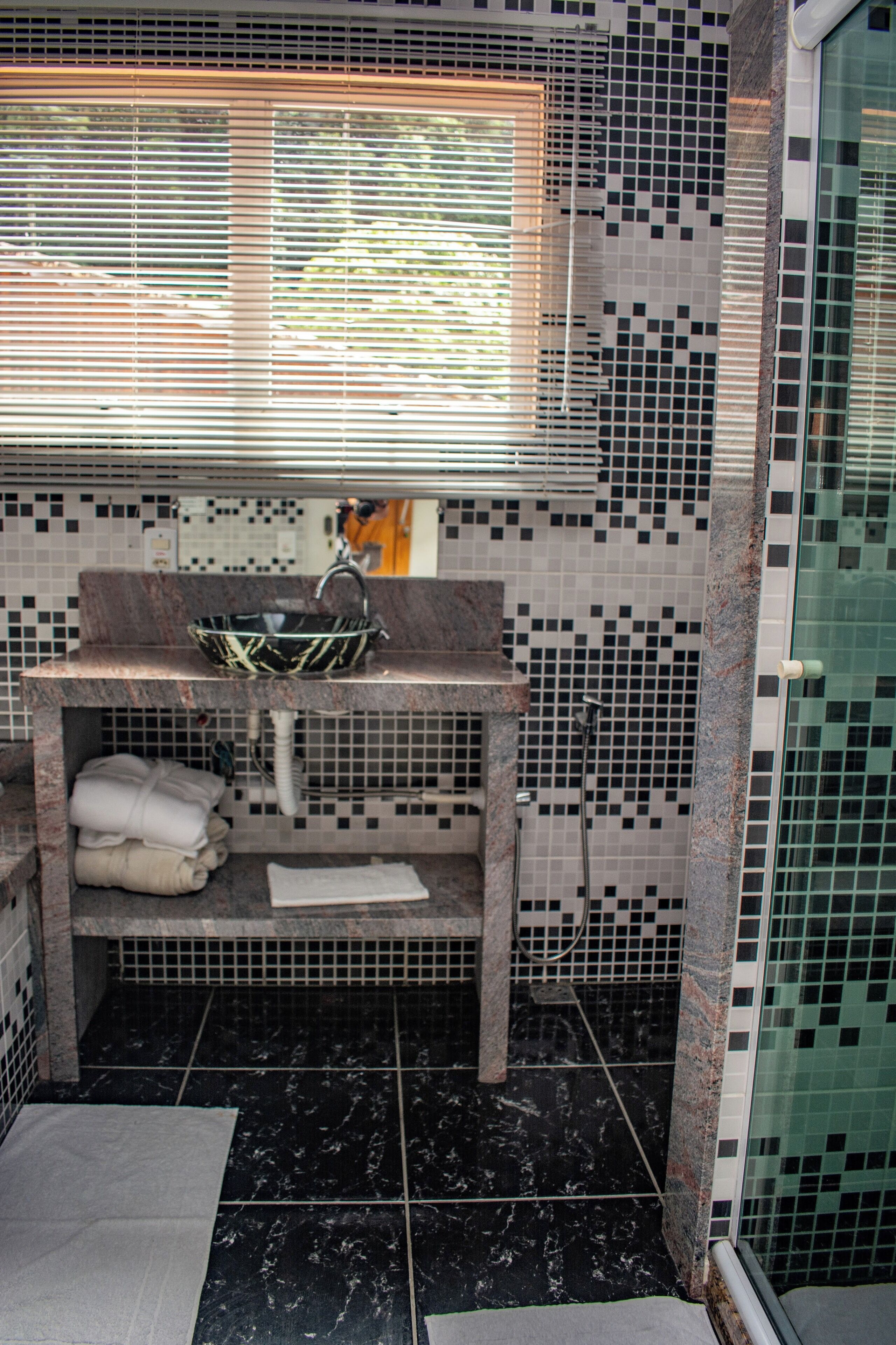 Un baño con mosaicos en el salpicadero, un lavabo con pileta y una zona de ducha.