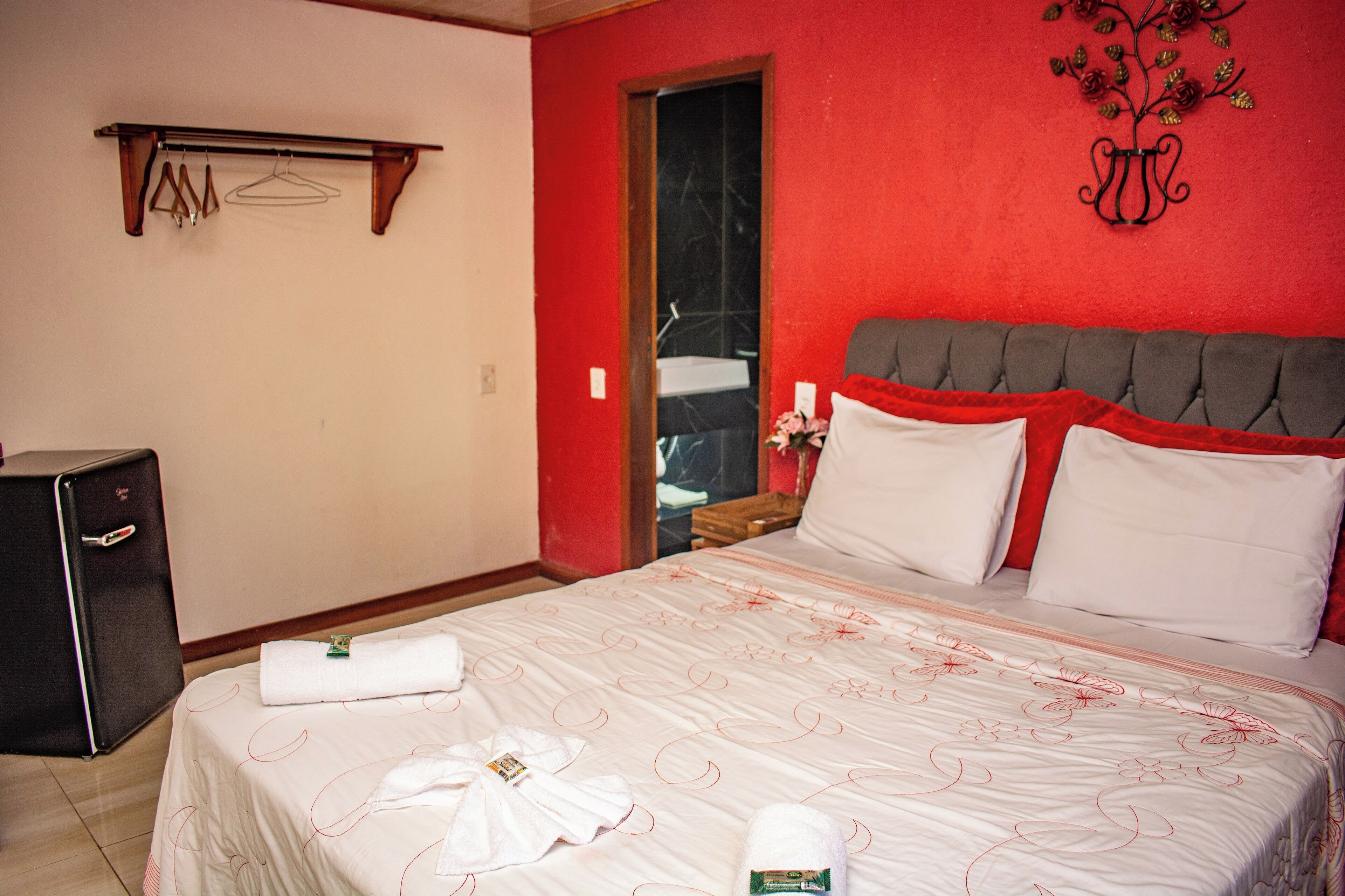 Una habitación de hotel con una cama, una mesita de noche, un espejo y un armario.