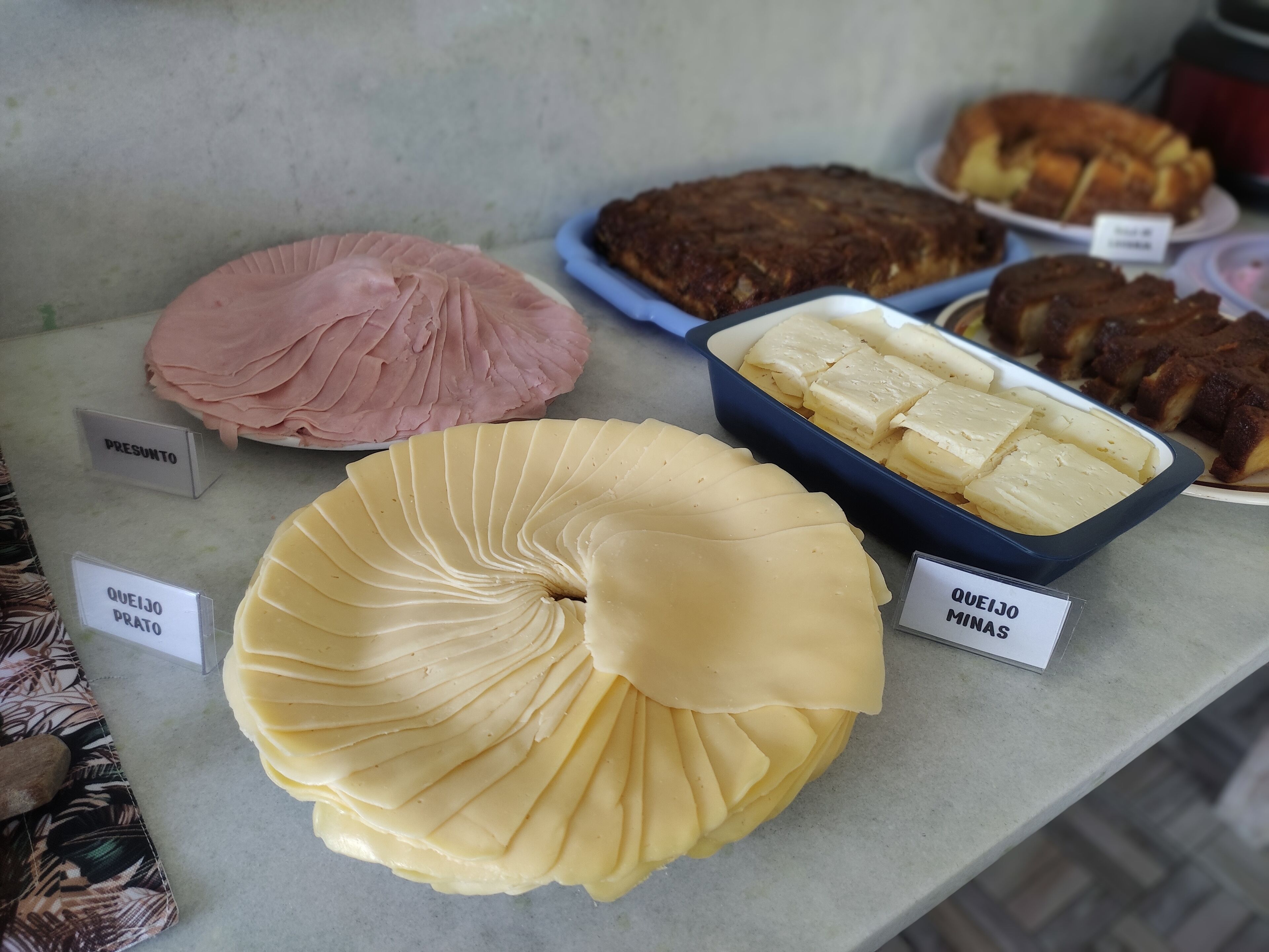 Una exhibición de diversos productos de queso y embutidos en una charcutería o pastelería.