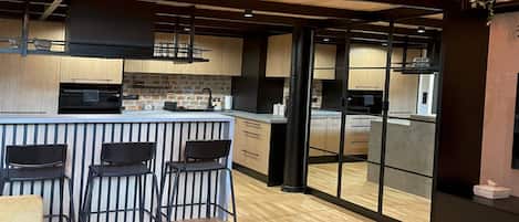 Una cocina moderna con una isla central, taburetes de bar y vistas a través de un ventanal.