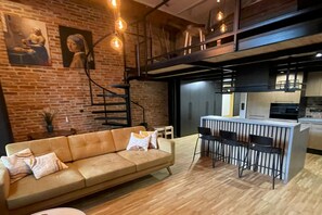 A modern interior with a leather sofa, a bar area, and exposed brick walls.