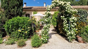 A garden with a gravel path, a white umbrella, and various flowering plants.