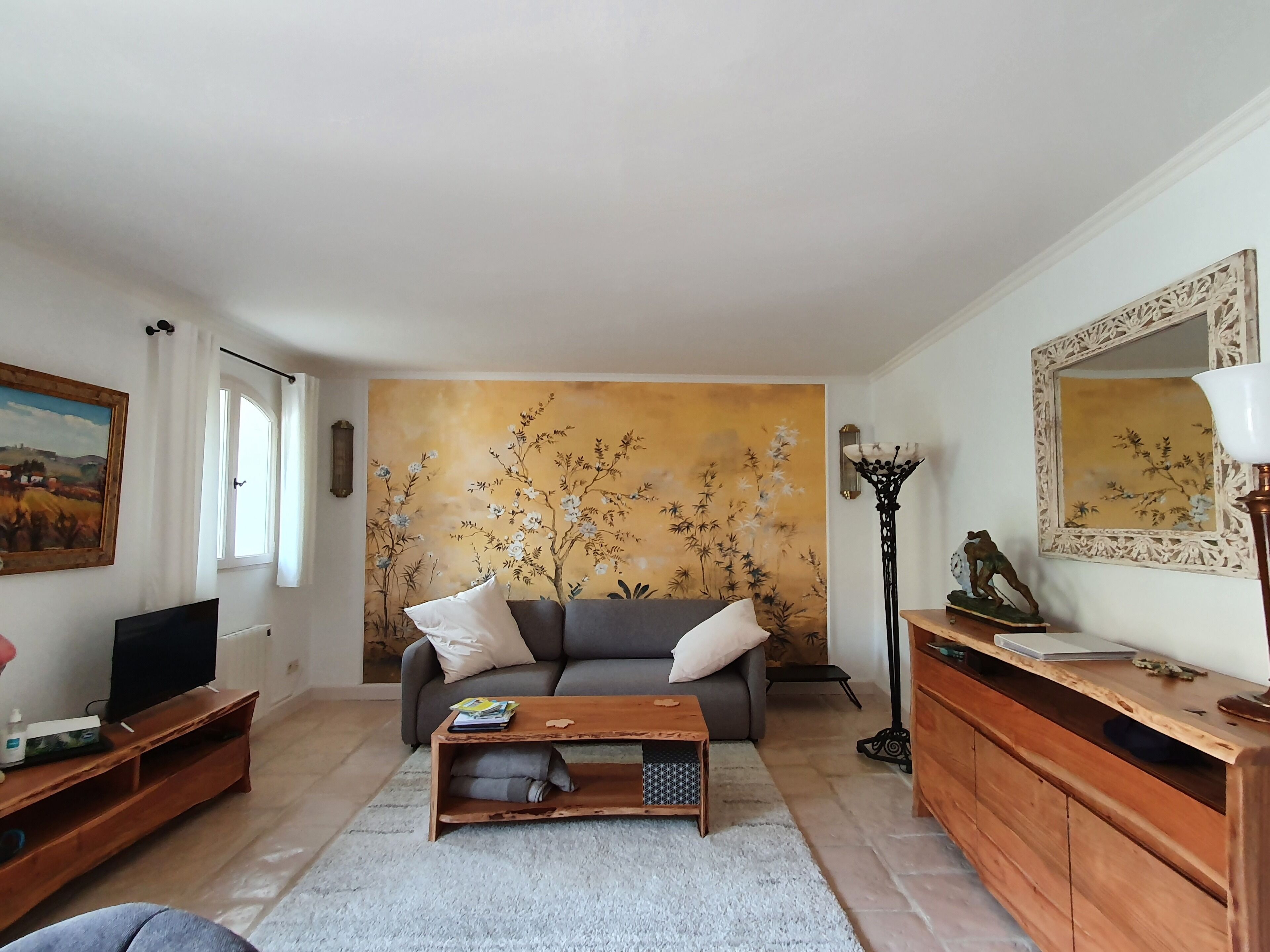 A living room with a sofa, coffee table, TV stand, and artwork on the walls.