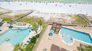 Un complejo turístico en la playa con piscina, tumbonas y sombrillas.