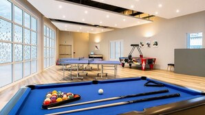 A pool table with balls and cues, a ping pong table, and a foosball table in a well-lit room with large windows. - Two Bedroom Apartment Easy Access (Ilfracombe)