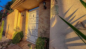 Ein Gebäudeeingang mit einem Ziegeldach, einer Wand mit geometrischem Muster und einem Schild mit der Aufschrift 'DAR SIALI'.