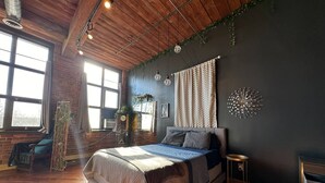 Een slaapkamer met een groot bed, een houten plafond en een bakstenen muur.