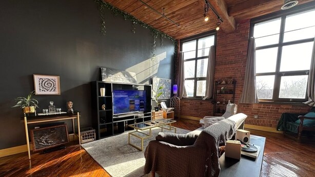 Een moderne woonkamer met een grote televisie, comfortabele zithoek en grote ramen.