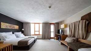 Una camera d'albergo con due letti, una scrivania, una televisione e un'ampia finestra.