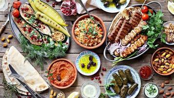 A variety of Middle Eastern dishes including grilled vegetables, kebabs, hummus, and stuffed grape leaves.