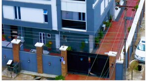 A multi-story building with a red roof, a gated entrance, and a visible balcony.