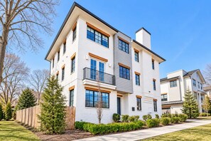 A multi-story residential building with a flat roof, large windows, and a balcony on the second floor. - Premium Home Rooftop Pool Table 13 Beds (Nashville)