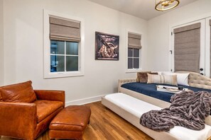 A bedroom with a bed, a leather sofa, and a window with a view. - Premium Home Rooftop Pool Table 13 Beds (Nashville)