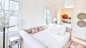 Une chambre à coucher avec un lit, des tables de chevet, une fenêtre et une lampe fixée au mur.