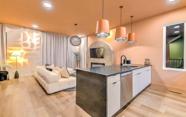 A modern kitchen with a central island, pendant lighting, and a built-in oven.