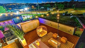 Eine Dachterrasse mit Holzboden, einer Couch, einem Sessel und einem kleinen Tisch.