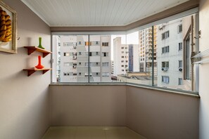 A corner balcony with a view of adjacent buildings, a framed picture, and two colorful vases on a shelf. - Apt 4min From sea in BC Close to Everything Rta042 (Balneário Camboriú)