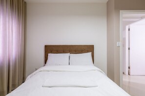 A neatly made bed with white linens in a room with a plain wall and a door to the right. - Apt 4min From sea in BC Close to Everything Rta042 (Balneário Camboriú)
