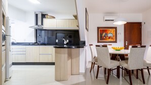 A modern kitchen with a central island, wooden cabinets, and a dining area with a table and chairs. - Apt 4min From sea in BC Close to Everything Rta042 (Balneário Camboriú)