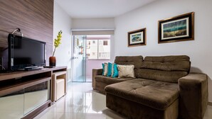 A modern living room with a flat-screen TV, a brown sofa with teal and white cushions, and two framed landscape paintings on the wall. - Apt 4min From sea in BC Close to Everything Rta042 (Balneário Camboriú)
