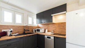 A modern kitchen with dark cabinets, a microwave, a dishwasher, and a refrigerator. - Le Duplex du Port: Parking, Paimpol Center (Paimpol)